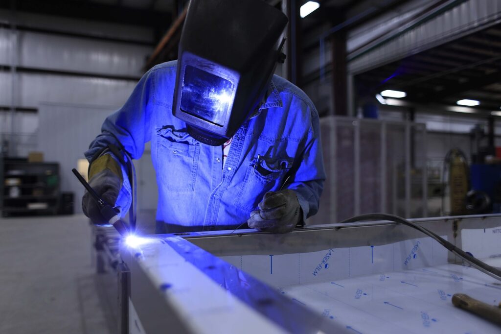 skilled welder in blue-collar work attire, welding metal in a workshop